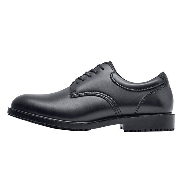 A black Shoes For Crews men's dress shoe with laces and a rubber sole.