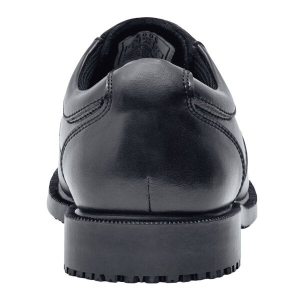 A black leather Shoes For Crews men's dress shoe with a rubber sole.
