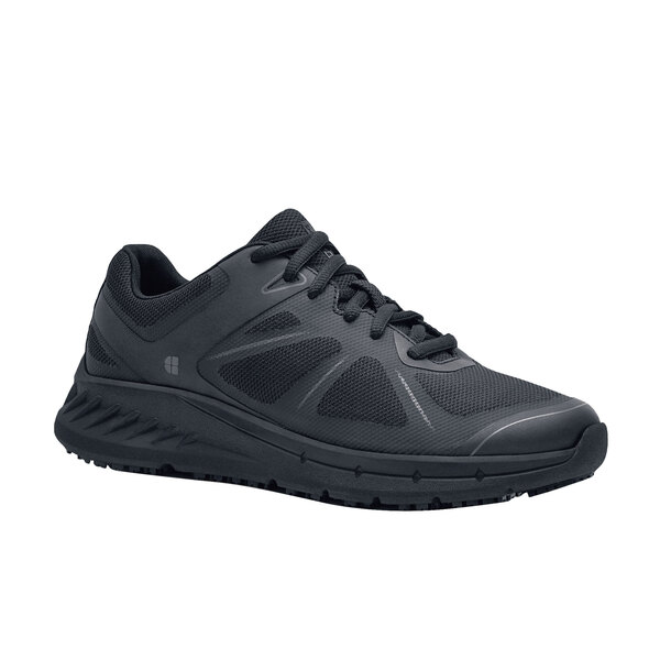 A black Shoes For Crews women's athletic shoe with a white background.