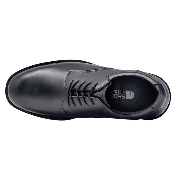 A black Shoes For Crews men's dress shoe with laces.