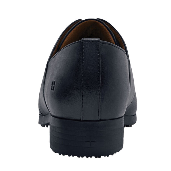A black Shoes For Crews Madison III dress shoe with a brown sole on a white background.