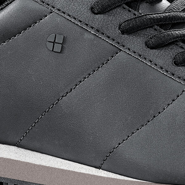 A close up of a black Shoes For Crews Avery athletic shoe with a white sole.