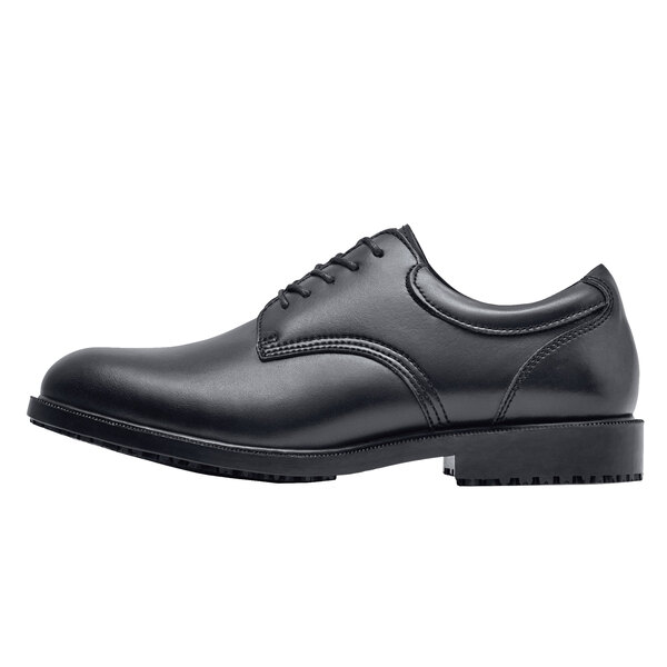 A black Shoes For Crews men's dress shoe with a rubber sole and laces.