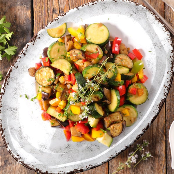 A French Mill melamine platter of vegetables on a wood table.