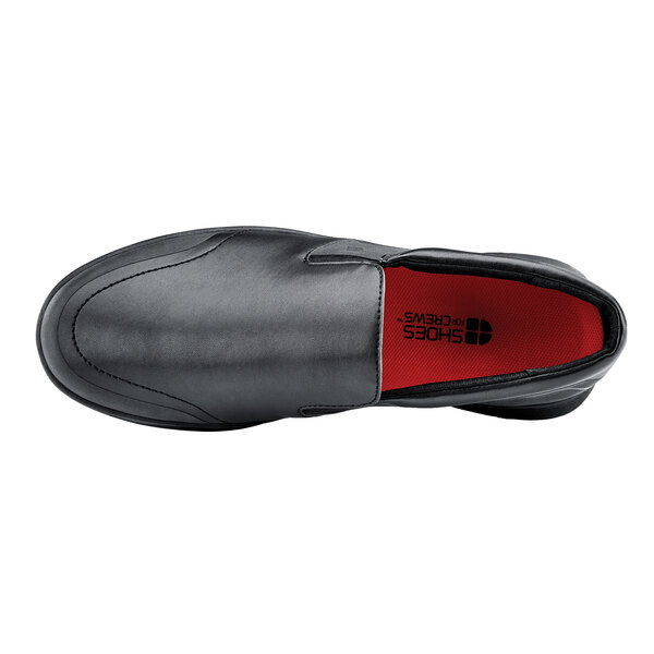 A black Shoes For Crews men's water-resistant soft toe shoe with a red sole.