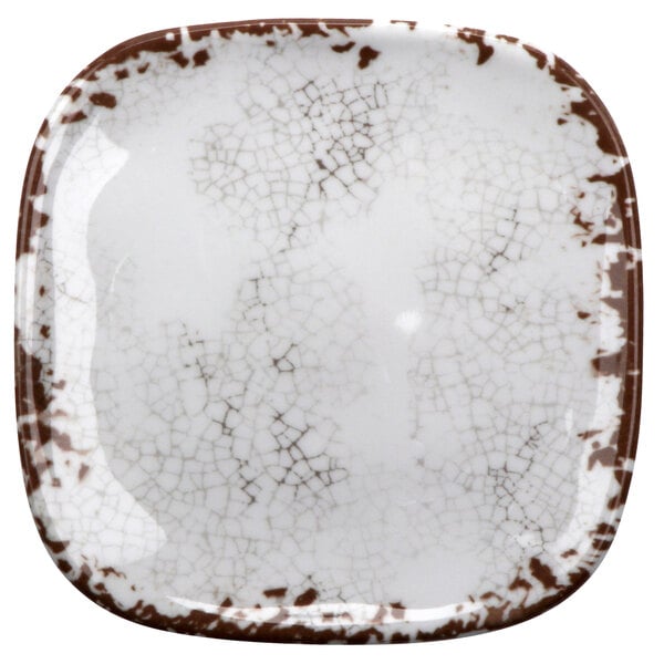 A white square melamine plate with brown speckles.