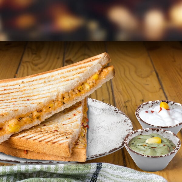 A grilled cheese sandwich with a side of dip in a ramekin.