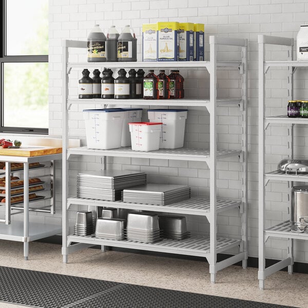A white Cambro Camshelving Premium unit with vented shelves holding containers.