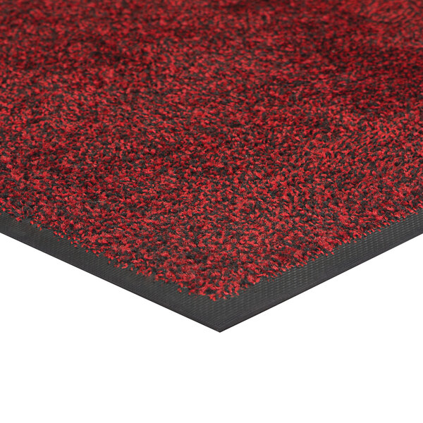 A white rubber-backed carpet mat with red and black spots.