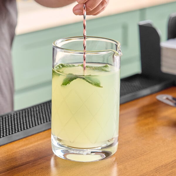 A bartender pouring a drink into a Barfly heavy-duty mixing glass.