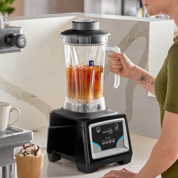 A commercial blender with a keypad control and a large clear container filled with iced liquid.