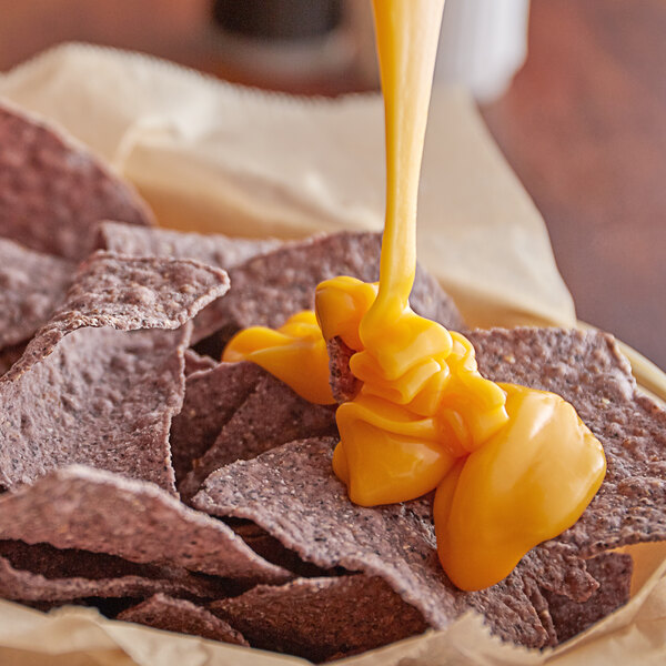 A bowl of chips with Muy Fresco Aged Cheddar nacho cheese sauce.