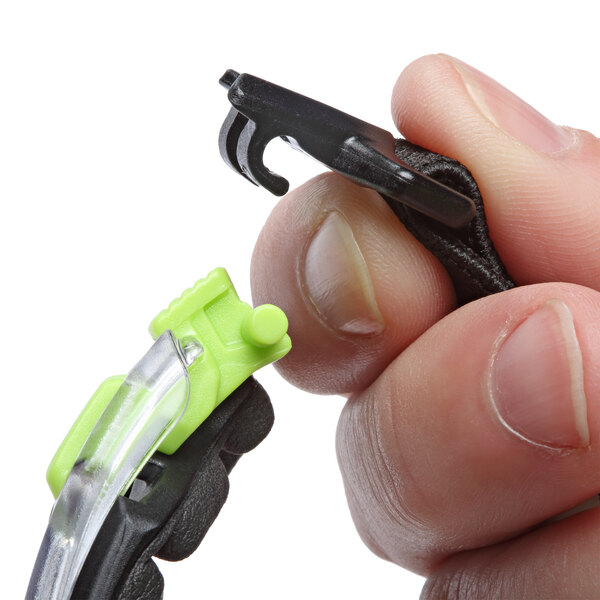 A hand holding black and green 3M Solus safety glasses with clear lenses.