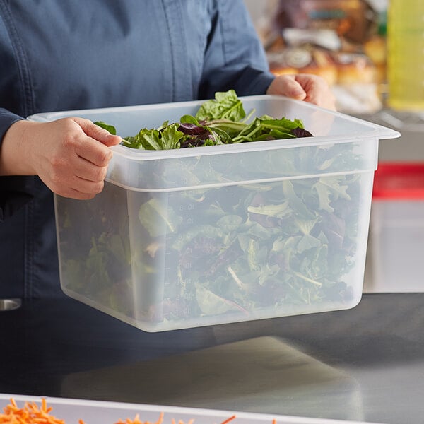 A woman holding a Cambro translucent plastic food pan filled with lettuce.