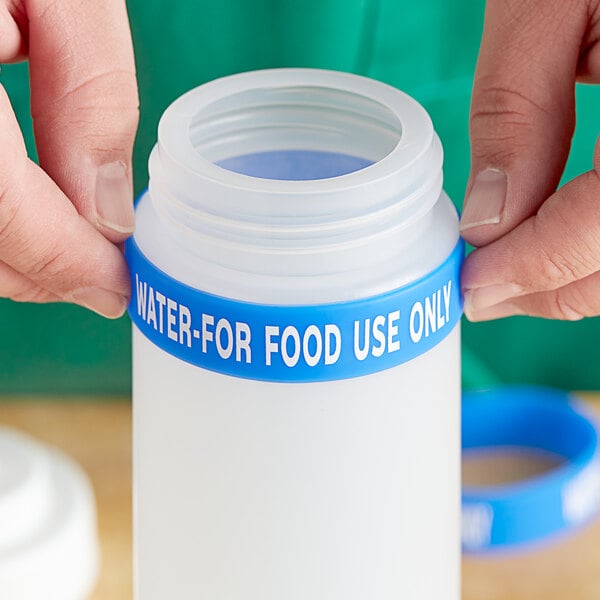 A person squeezing a blue silicone band onto a water bottle.