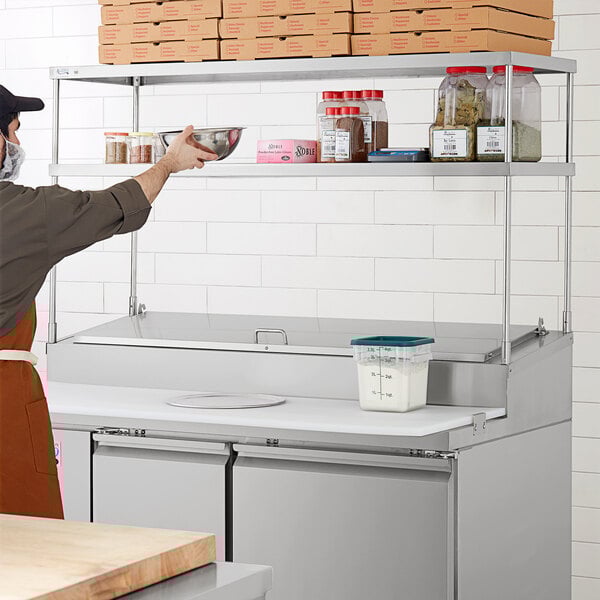 A stainless steel double deck overshelf on a counter in a professional kitchen.