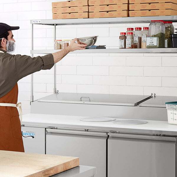 An Avantco stainless steel double deck overshelf on a counter in a professional kitchen.