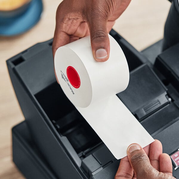 A hand holding a roll of Iconex MAXStick PlusD thermal paper.