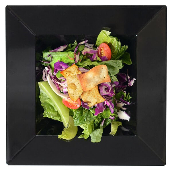 a salad in a square black plate