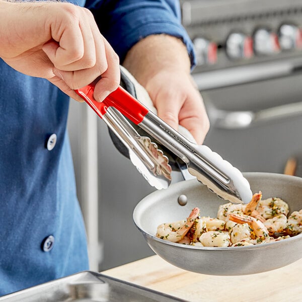 A person holding Carlisle tongs to a pan of shrimp.