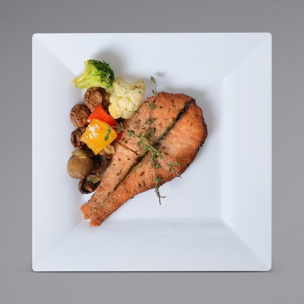 a piece of cooked salmon with vegetables on a white plate