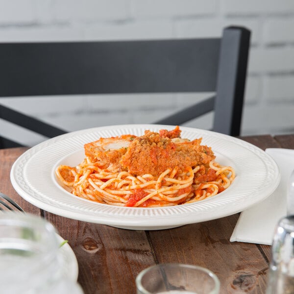 An Ivory (American White) china soup dish filled with spaghetti and meatballs on a table.