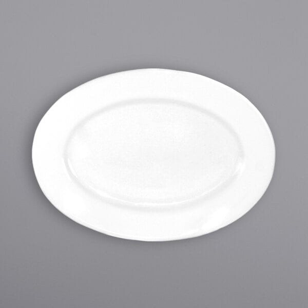 An International Tableware white porcelain oval platter with a wide rim on a gray surface.