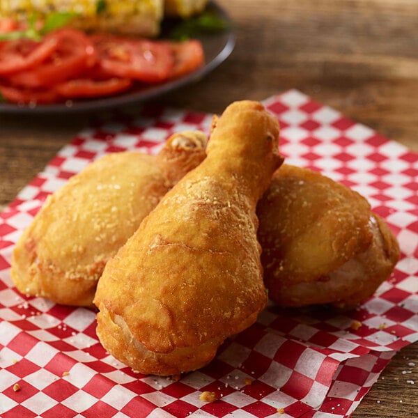 Fried Golden Dipt chicken legs on a checkered napkin.