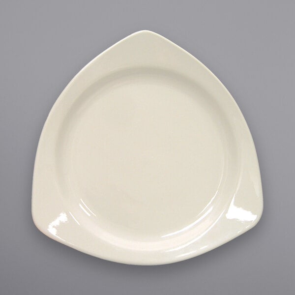 A white International Tableware stoneware plate with a triangle shape.