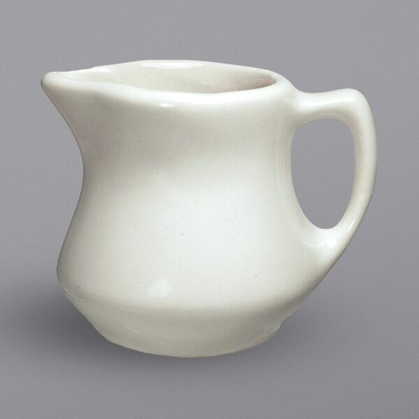 An International Tableware Roma ivory stoneware creamer with a handle.