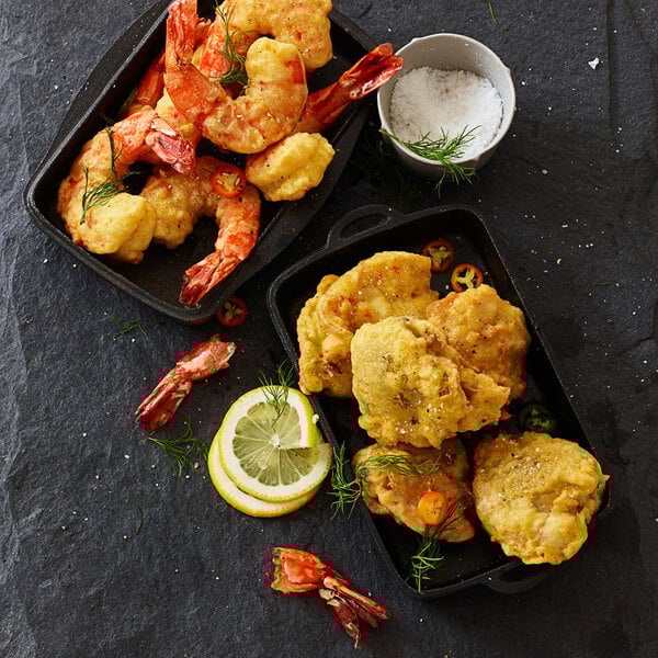 A plate of fried Golden Dipt clam fry shrimp with a lemon wedge.