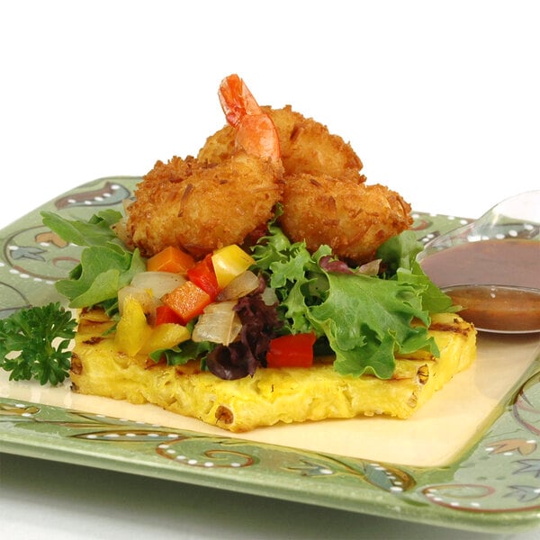 A plate of shrimp and vegetables with brown sauce on a table, breaded with Golden Dipt Tropical Rum Coconut Breader.