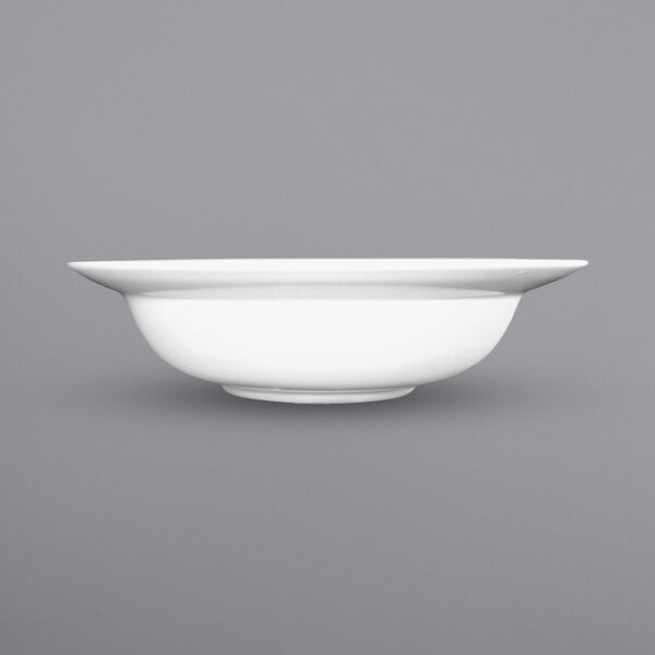 A close up of an International Tableware Bristol white porcelain pasta bowl with a wide rim.