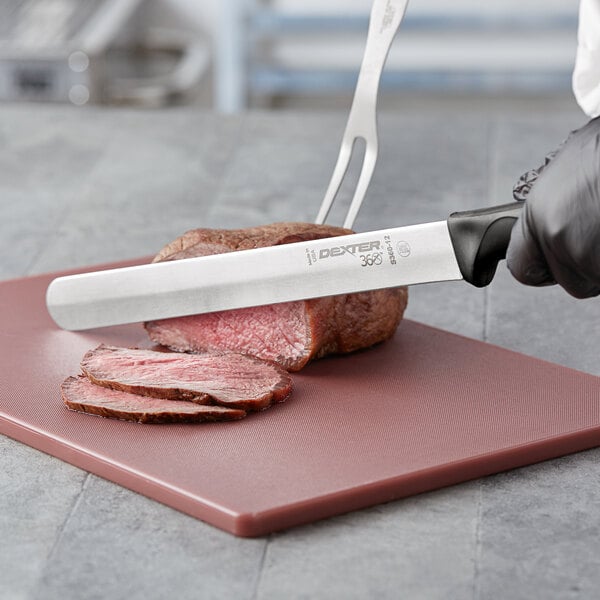 A person using a Dexter-Russell slicing knife to cut meat on a cutting board.