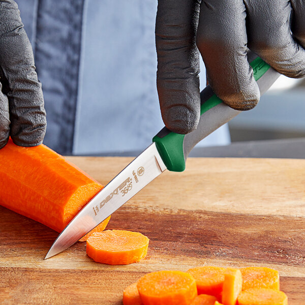 A person in black gloves using a Dexter-Russell paring knife to cut a carrot.