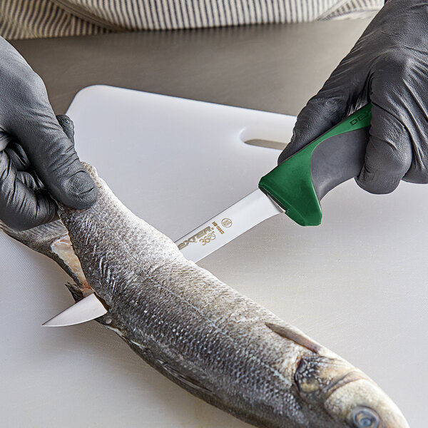 A person in gloves using a Dexter-Russell narrow flexible boning knife to cut fish.