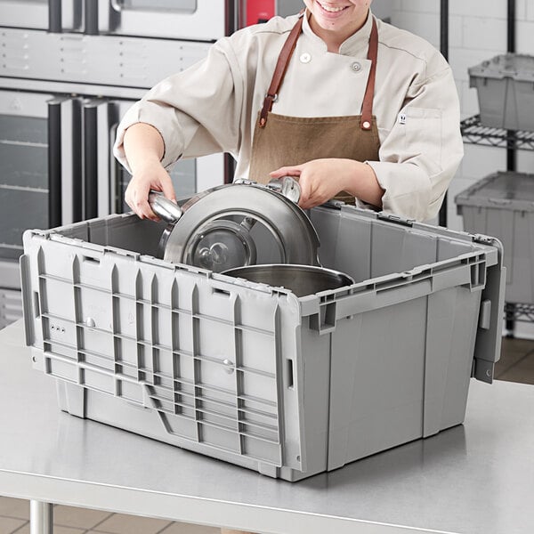 A woman in a chef's uniform using an Orbis Stack-N-Nest tote to store a pot.