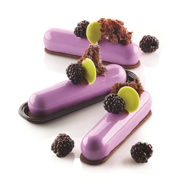 Three purple Silikomart desserts with blackberries and chocolate on top.