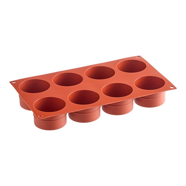 A red Silikomart silicone baking mold with 8 cylindrical compartments.