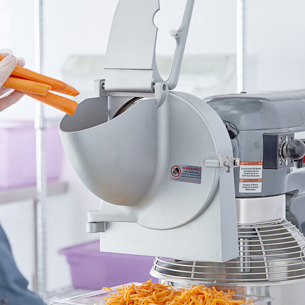 A person using an Avantco Shredder Attachment to shred carrots.