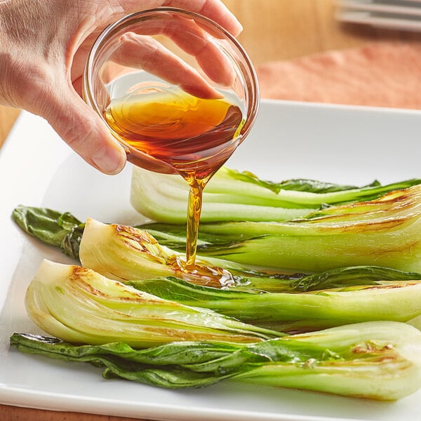 Sesame oil being poured on bok choy