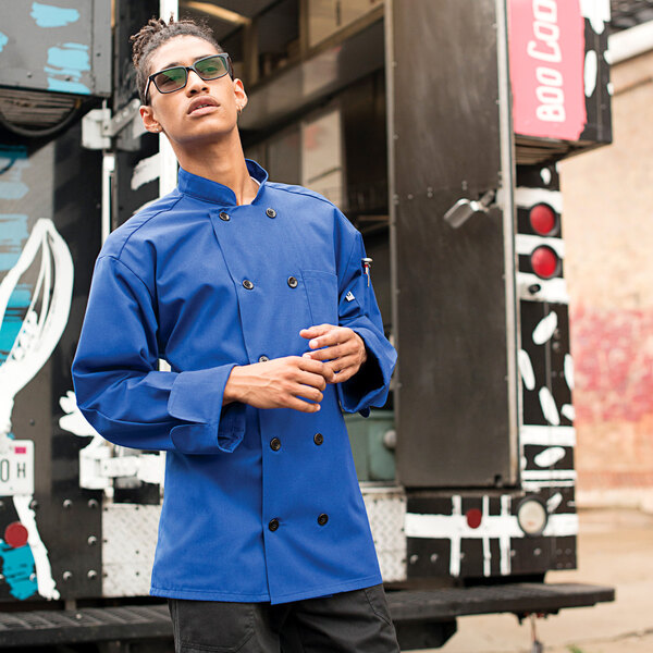 A man wearing a royal blue Uncommon Chef long sleeve chef coat.