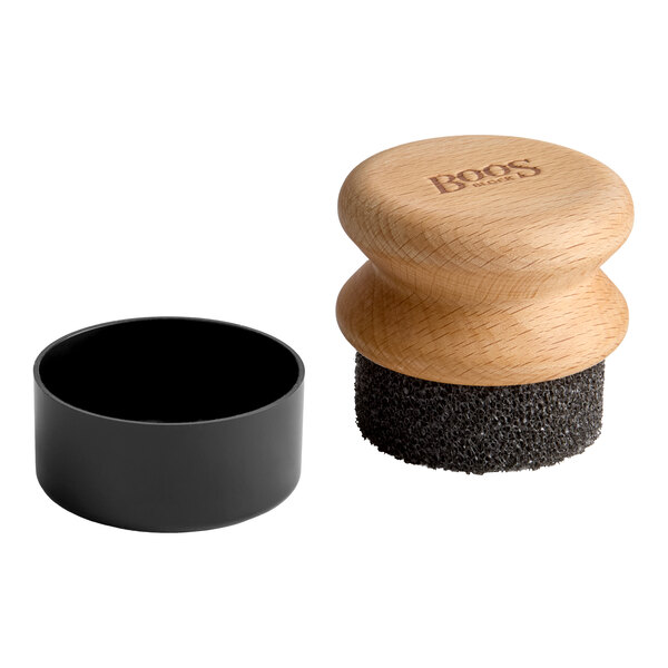 A round wooden-handled applicator with a textured black scrubbing pad and a separate black plastic cap, shown on a white background.