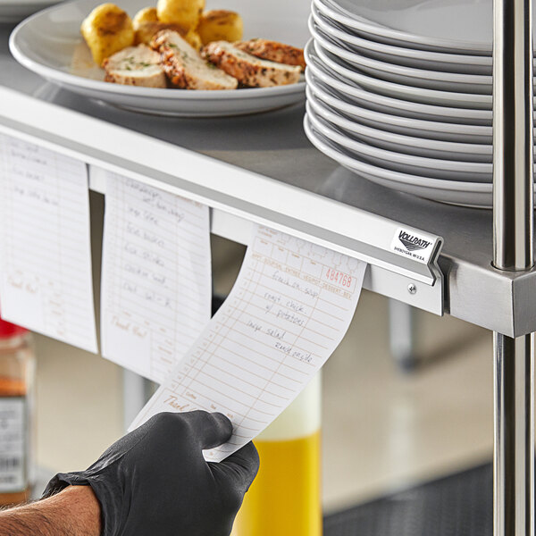 A hand holding a receipt above a counter with food on it.