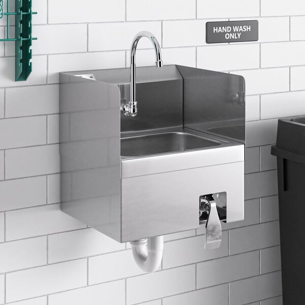 A Regency wall mounted hand sink with knee operated valves and side splashes.