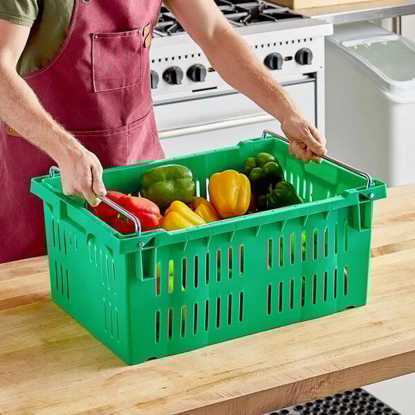 A man holding a green Orbis agricultural crate full of vegetables.