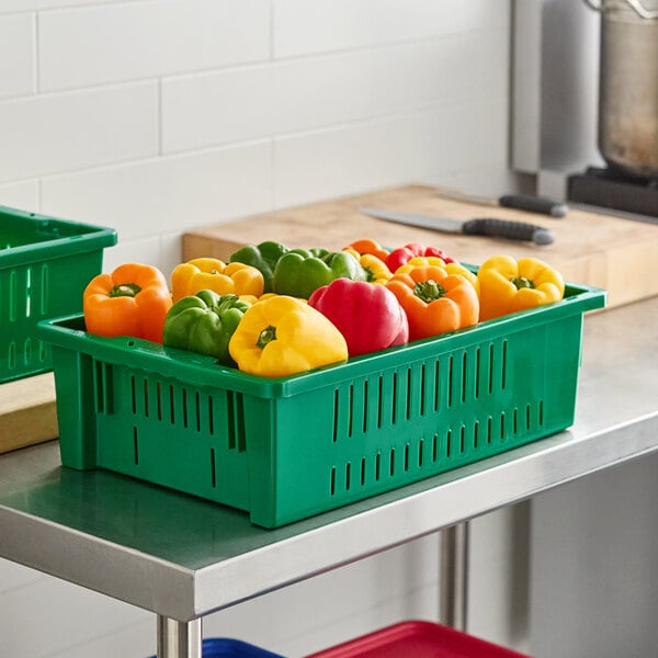 Two green Orbis agricultural crates filled with bell peppers on a green counter.