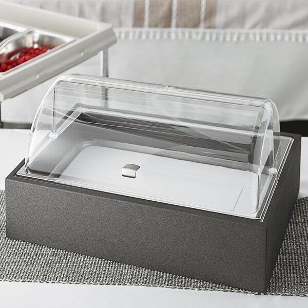 A Vollrath display kit with a clear cover on a wooden base over a tray of food.