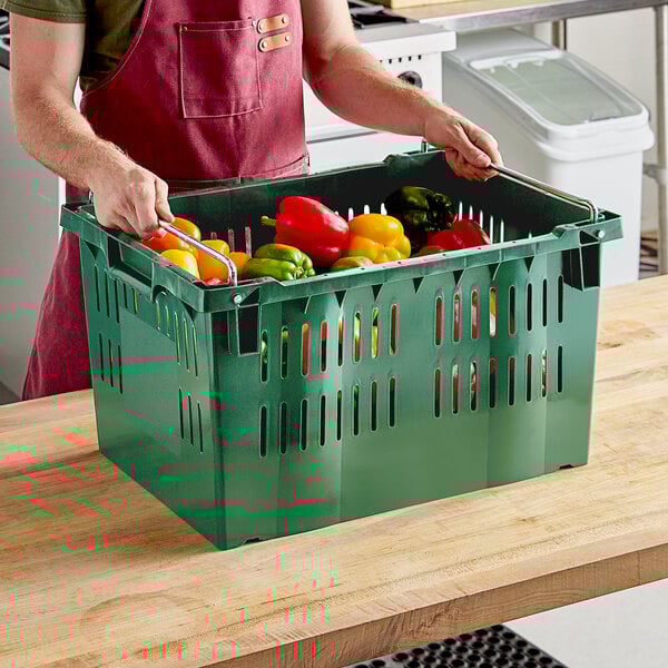A man holding a green Orbis Stack-N-Nest crate full of vegetables.