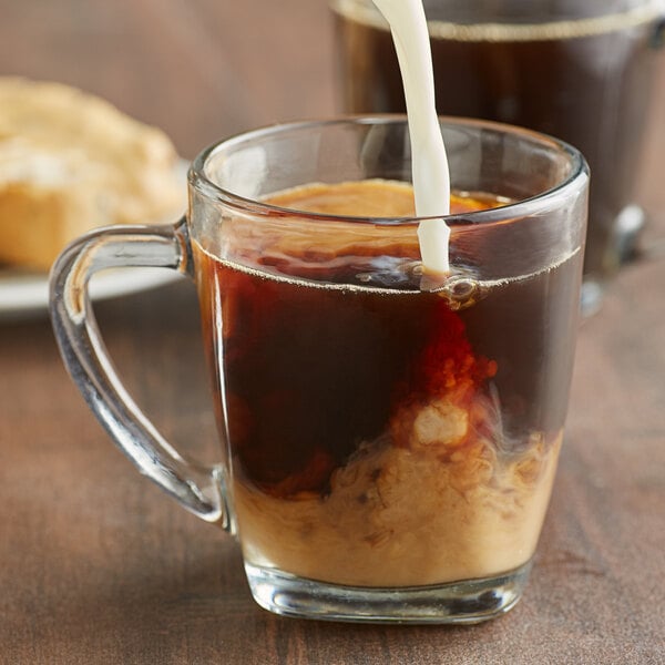 A glass mug filled with Caribou Coffee Obsidian Blend whole bean coffee and cream